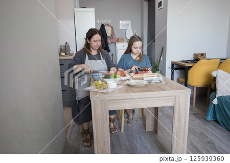 Mother and daughter preparing lunch together in kitchen Mother and daughter preparing lunch together in kitchen 125939360