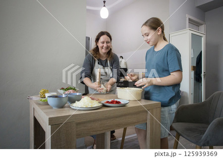 Happy family indoor. Mother And Daughter Baking Pizza In Kitchen Together Happy family indoor. Mother And Daughter Baking Pizza In Kitchen Together 125939369
