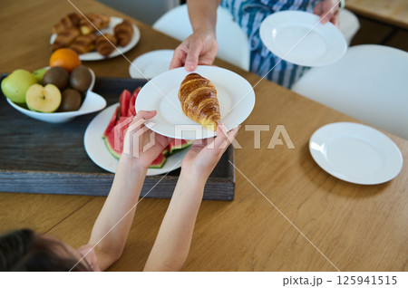 Family Sharing Breakfast With Fresh Croissants and Fruit at a Sunny Home Family Sharing Breakfast With Fresh Croissants and Fruit at a Sunny Home 125941515