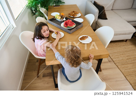Children Enjoying a Healthy Breakfast at a Home Dining Table Children Enjoying a Healthy Breakfast at a Home Dining Table 125941524