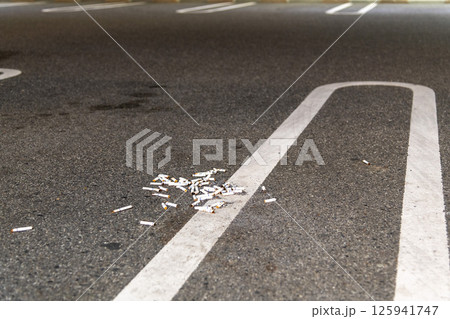 車の灰皿から直接不法投棄され駐車場に取り残されたタバコの吸い殻 車の灰皿から直接不法投棄され駐車場に取り残されたタバコの吸い殻 125941747