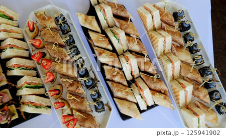 Gourmet canapes featuring salmon and cucumber resting on crisp white tablecloth, presenting refined culinary artistry at sophisticated catered gathering 125941902