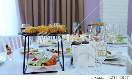Elegant restaurant table featuring golden profiteroles, canapes, appetizers, and empty wine glasses, presenting refined dining atmosphere Elegant restaurant table featuring golden profiteroles, canapes, appetizers, and empty wine glasses, presenting refined dining atmosphere 125941997