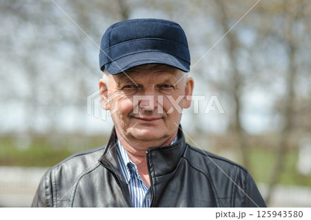 Pensioner in a hat with a visor, jacket and shirt on the street. In sunny weather, the pensioner is smiling and enjoying life. Pensioner in a hat with a visor, jacket and shirt on the street. In sunny weather, the pensioner is smiling and enjoying life. 125943580