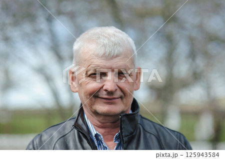 A well-dressed elderly man is smiling. A gray-haired man stands on the street. A well-dressed elderly man is smiling. A gray-haired man stands on the street. 125943584