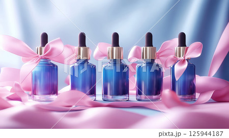 Group bottles for oil, concentrate, serum, blank brand label, pink satin ribbon and gold cap on blue background, minimalist design. Cosmetics advertising concept 125944187