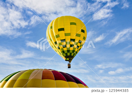 Colorful hot air balloon flying over blue sky with white clouds 125944385
