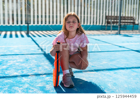 Young girl confidently posing on the tennis court with racket. 125944459