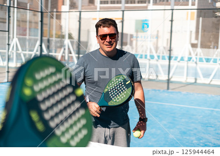 Man enjoys playing padel under the sun on a bright day. Man enjoys playing padel under the sun on a bright day. 125944464