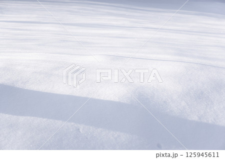 Snow-covered ground with subtle shadow and smooth undisturbed surface under daylight 125945611