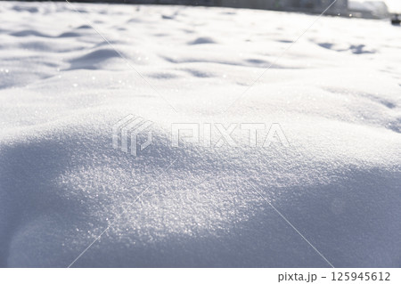 Soft white snowdrift surface sparkling under low winter sunlight in closeup 125945612