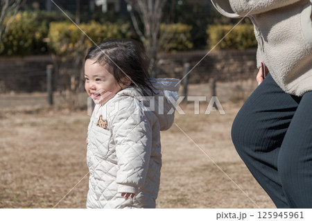 【相模原市立麻溝公園の芝生広場で遊ぶ1歳児とおかあさん】 125945961