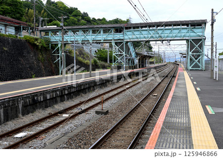 のどかな駅のホームから跨線橋と線路の先をみる 125946866
