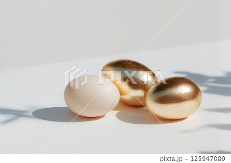 Golden and white Easter eggs on flat white surface. Minimal interior in light colors on background Golden and white Easter eggs on flat white surface. Minimal interior in light colors on background 125947089