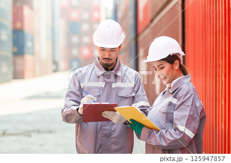 Asian male and female customs officers are currently conducting inspections of containers within the container yard. Officers are also conducting a count of inbound and outbound cargo. 125947857