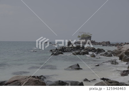 A Serene Coastal Landscape Featuring a Rocky Shoreline and Overcast, Cloudy Skies Above 125948463