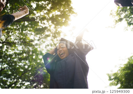 Female student in graduation gown has an excited and delighted expression as she receives her diploma upon graduating from university. African woman feels proud about her academic achievement. 125949300