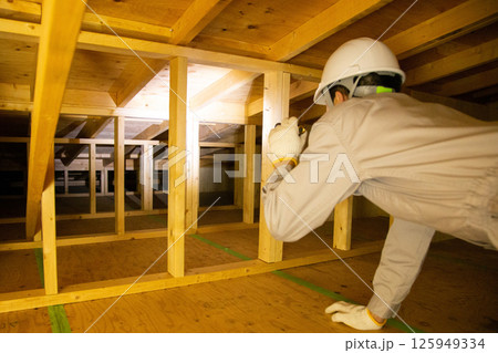 住宅の屋根裏で業務にあたる業者 住宅の屋根裏で業務にあたる業者 125949334