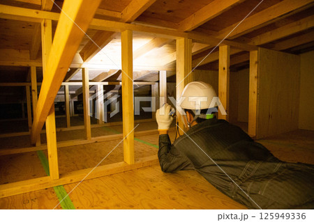 住宅の屋根裏で業務にあたる業者 125949336