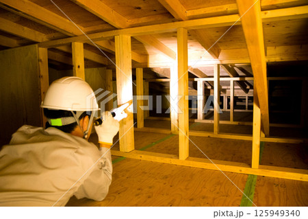 住宅の屋根裏で業務にあたる業者 125949340