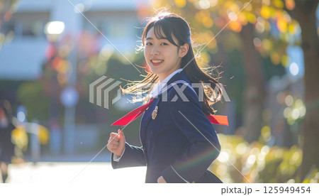 秋の光に包まれる女子学生の笑顔 ─ 制服姿で振り返る爽やかな通学シーン 125949454