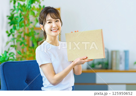 リビングでメール便の荷物を確認する若い女性 リビングでメール便の荷物を確認する若い女性 125950652