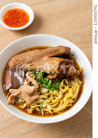 egg noodles with stewed and braised duck in brown soup 125950741