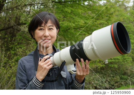 望遠カメラを持つ笑顔の中年女性 カメラ目線 望遠カメラを持つ笑顔の中年女性 カメラ目線 125950900