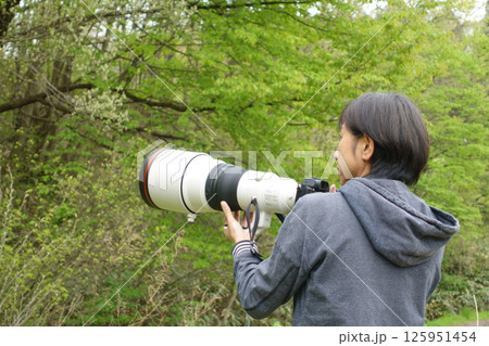 カメラを構え被写体を探す女性の後姿 野鳥撮影 カメラを構え被写体を探す女性の後姿 野鳥撮影 125951454