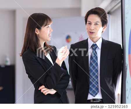 プレゼン内容を確認し合うスーツ姿の若い男女 125952163