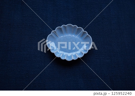 手紡ぎ藍染の布の上に置かれた小皿 125952240