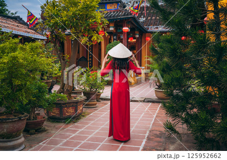 Back of a woman tourist traveler in a Vietnamese cone hat at Buddhist temple in Hoi An in Vietnam in Asia 125952662