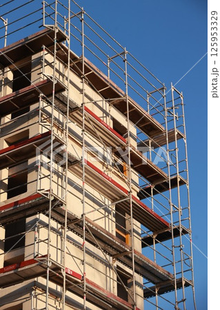 A building under construction with scaffolding on the side 125953329