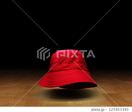 Red bucket hat on wooden floor, black background. Red bucket hat on wooden floor, black background. 125953393