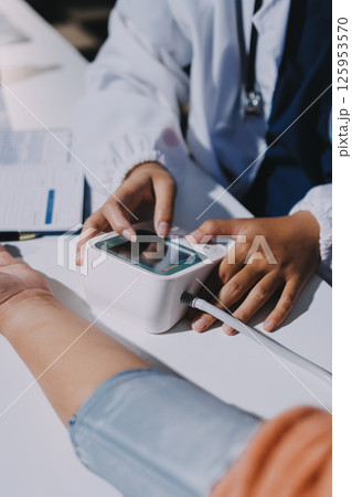 Nurse measuring blood pressure of elderly woman at table, closeup. Assisting senior generation Nurse measuring blood pressure of elderly woman at table, closeup. Assisting senior generation 125953570