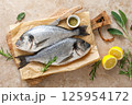 Fresh raw sea bream fish or dorado fish with lemon and herbs, top view 125954172
