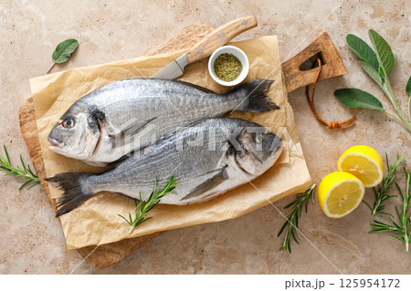 Fresh raw sea bream fish or dorado fish with lemon and herbs, top view Fresh raw sea bream fish or dorado fish with lemon and herbs, top view 125954172