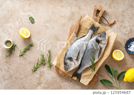Fresh raw sea bream fish or dorado fish with lemon and herbs, top view Fresh raw sea bream fish or dorado fish with lemon and herbs, top view 125954687