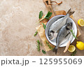 Fresh raw sea bream fish or dorado fish with lemon and herbs, top view 125955069