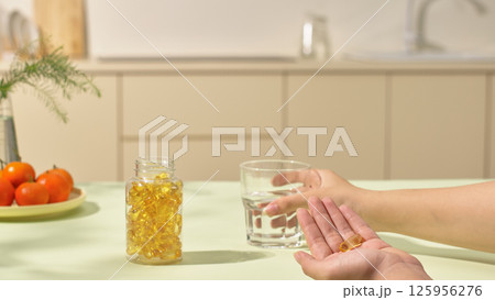 Daily medication activity as prescribed by a doctor. A medicine bottle, opened and placed on the kitchen table. Plate of fresh green vegetables and a potted indoor plant that is blurred. Copy space. 125956276