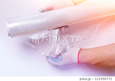 Stretch film and cardboard packaging on a white background top view. Packaging of goods. A knife for cutting cardboard. Stretch film and cardboard packaging on a white background top view. Packaging of goods. A knife for cutting cardboard. 125956772