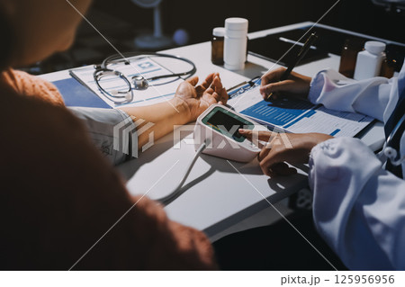 Nurse measuring blood pressure of elderly woman at table, closeup. Assisting senior generation Nurse measuring blood pressure of elderly woman at table, closeup. Assisting senior generation 125956956