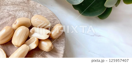 Detailed close-up of golden-brown pili nuts on rustic wooden board showcasing their unique texture 125957407