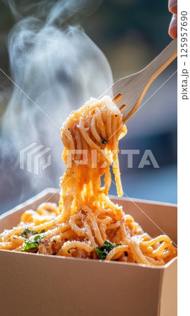 Close-up of steaming pasta being lifted from a recyclable carton with a wooden fork 125957690
