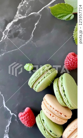 Colorful French Macaroons with Fresh Raspberries and Mint Leaves on a Dark Marble Surface for a Delicious Dessert Experience Healthy Eating Concept 125957714