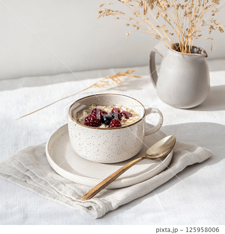 Simple breakfast featuring oatmeal topped with fresh berries, beautifully arranged with sunlight filtering through Simple breakfast featuring oatmeal topped with fresh berries, beautifully arranged with sunlight filtering through 125958006