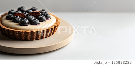 Glistening blueberries atop silky vanilla custard in a flaky tart 125958289