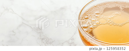 Nutrient-dense bone broth pouring into glass cup, resting on marble countertop, highlighting healing properties for wellness-focused consumers and biohacking enthusiasts 125958352