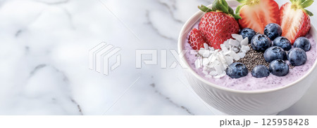 Colorful smoothie bowl garnished with strawberries, blueberries, coconut flakes, chia seeds on marble surface, representing nutritious breakfast trend Colorful smoothie bowl garnished with strawberries, blueberries, coconut flakes, chia seeds on marble surface, representing nutritious breakfast trend 125958428