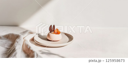 Elegant mousse dessert with chocolate rabbit detail on a pastel linen backdrop in warm daylight Elegant mousse dessert with chocolate rabbit detail on a pastel linen backdrop in warm daylight 125958673